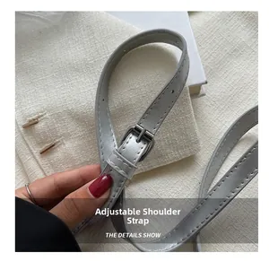 Detail of adjustable grey leather shoulder strap with silver buckle and stitching