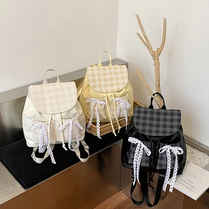 Three minimalist chic backpacks in beige, yellow, and black with lace bow detailing