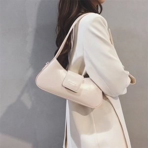 Close-up of minimalist cream white faux leather baguette bag worn over the shoulder