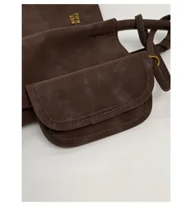 Detail of matte coffee bucket bag with a mini pouch and gold logo lettering