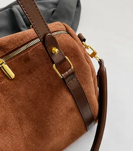 Détails d'un sac Boston en daim avec garniture en cuir et quincaillerie dorée