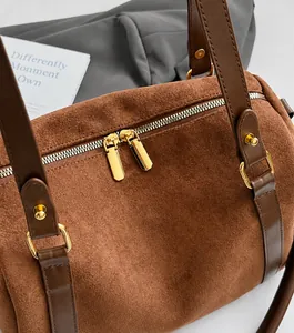 Détail du sac Boston en daim marron montrant les doubles fermetures éclair dorées fluides