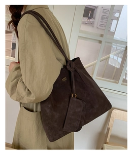 Detail of dark brown matte leather tote bag with gold COIH 2DN logo and small clutch