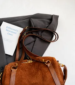 Détail du sac Boston en daim caramel avec ferrures dorées et bandoulière en cuir brun