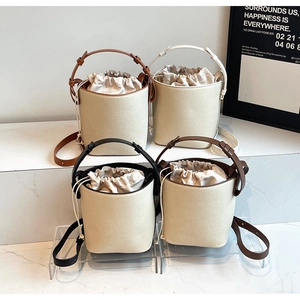 Detalle de cuatro bolsos saco de lona con cierre de cordón en un soporte de exhibición