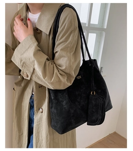 Detail of black faux suede tote bag featuring side gold-tone hardware and chic buckle trim