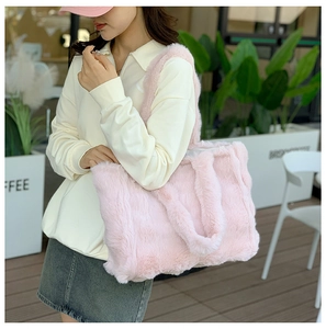 Vue latérale détaillée d'un grand sac cabas en fausse fourrure rose porté par un mannequin