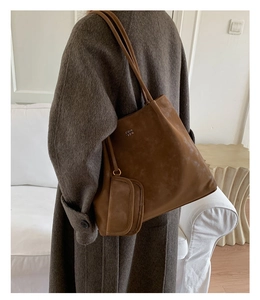 Brown faux suede tote bag with small matching purse shown on model shoulder in a cozy room