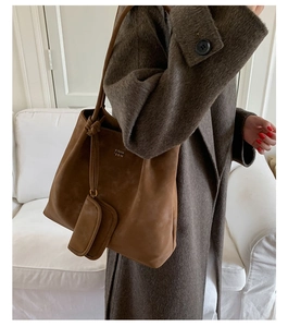 Detail of dark brown suede shoulder bag with coin pouch worn on grey woolen coat