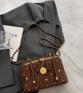 Détail du sac boîte matelassé avec strass et pendentif en forme de camélia