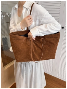 Close-up of a brown frosted suede tote bag showing soft texture and long shoulder straps