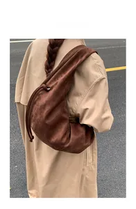 Vue arrière d'un mannequin portant un sac demi-lune en daim marron foncé à nœuds