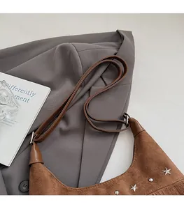 Détail d'un sac bandoulière en daim marron avec rivets étoiles argentés et franges pendantes