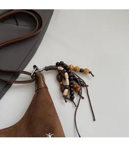 Détail du sac seau en daim marron avec rivet étoile et pompons perlés bohèmes