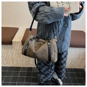 Détail du sac Boston en daim marron avec des bandoulières en cuir noir élégantes
