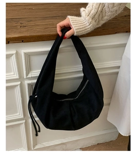 Détail d'un sac hobo en daim noir avec fermeture éclair argentée et cordon décoratif