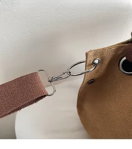 Detail of high-gloss silver metal hook and textured khaki canvas on retro messenger bag
