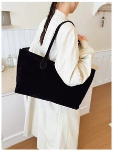 Close-up of a large black matte suede tote bag worn on shoulder for a stylish commuter look