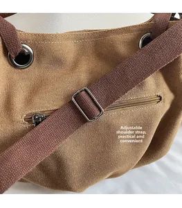 Detail of adjustable canvas strap with metal buckle and front zipper pocket on khaki tote
