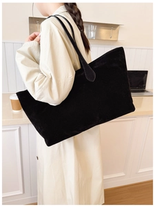 Large black suede tote bag with slim straps shown on a model in a beige trench coat