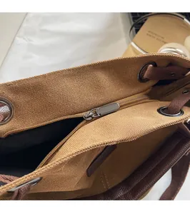 Detailed macro view of the smooth gunmetal zipper and woven strap of this canvas tote bag