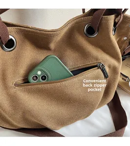 Detalle del bolsillo trasero con cremallera en un bolso tote de lona caqui para móvil