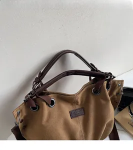 Detail of canvas tote bag with leather handle and metallic eyelet fasteners