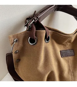 Close-up of brown canvas tote with leather handles and reinforced metal rivets