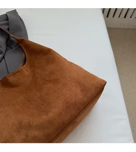 Detailed close-up showing soft brown suede texture and stitching on the tote bag