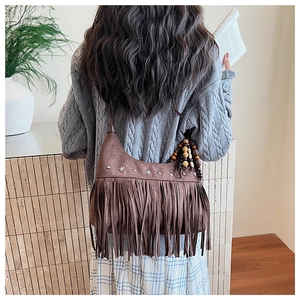 Close-up of brown suede tassel bag with star rivets and beaded detail for women