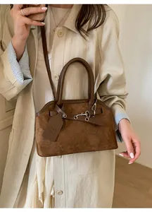 Detail of vintage brown suede crossbody shell bag with silver metal buckles and double handles