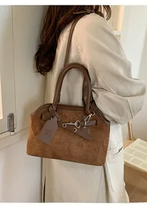 Detail of dark brown suede tote bag with leather handle and silver metal chain buckle