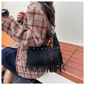 Détail du sac seau bohème noir à franges avec clous étoilés et breloques à pompons