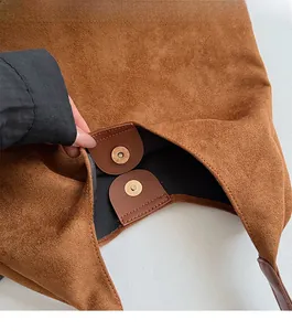 Close-up of the vintage gold magnetic clasp and suede texture on a brown tote bag