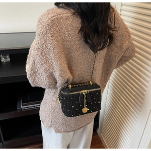 Détail du sac boîte noir matelassé avec cristaux et pendentif de rose dorée