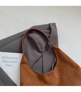 Detail of the soft brown suede hobo bag featuring thin dark brown leather shoulder straps