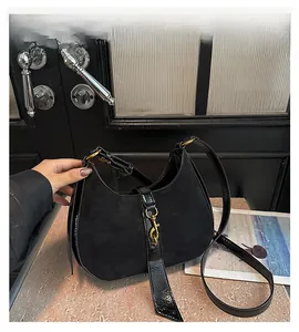 Detail of black crescent hobo bag with gold piston clasp and croc-textured panel