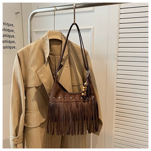 Close-up of brown suede hobo bag with long fringe tassels and star metal rivets