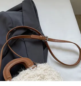 Close-up of white plush box bag featuring brown leather strap and silver metal buckle