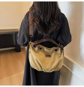 Model view of a khaki canvas hobo bag with wide brown shoulder strap and leather handles