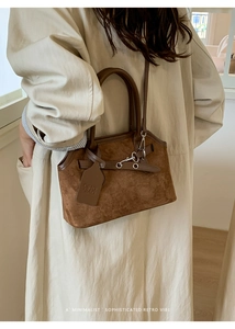 Close-up of retro brown suede tote bag with leather handles and metallic lock details