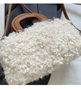 Detailed view of white faux shearling fur boston bag with brown leather handles