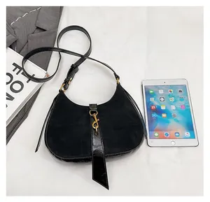 Size comparison of a black crescent hobo bag with gold hardware next to an iPad mini