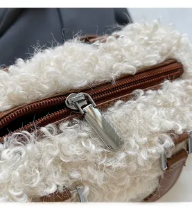 Detail of silver metal zipper and brown leather trim on a white fuzzy fleece bag