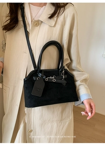 Detail of black suede and leather crossbody bag with silver buckles and a minimalist logo tag