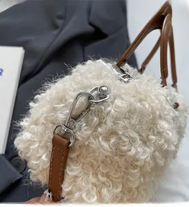 Close-up of white plush box bag featuring brown leather handle and silver metal hardware