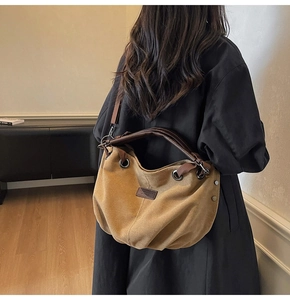 Detail of a large khaki canvas messenger bag with brown leather handles and shoulder strap