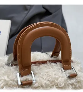 Macro detail of white faux fur handbag featuring brown leather handle and silver metal buckle