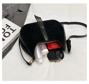 Interior storage space of the black suede crescent bag showing phone and cosmetics