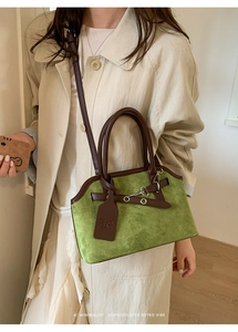 Detail of vintage green suede shell bag with brown leather handles and brand tag